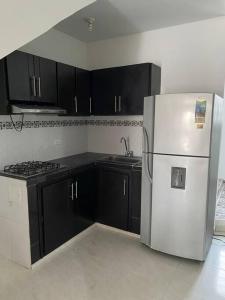 a kitchen with black cabinets and a white refrigerator at Apartamento familiar Obdulio in Villavicencio