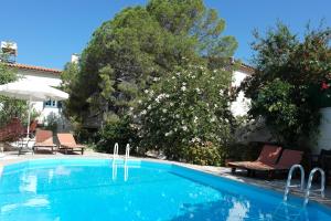 a blue swimming pool with chairs and an umbrella at Villa Kynthia in Panormos Rethymno