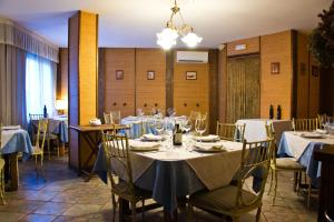 a dining room with tables and chairs with white tablecloths at Hospedium La Posada de Bayuela in Castillo de Bayuela