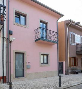 Casa rosa con balcón en una calle en Douro Afurada Boutique Apartments, en Vila Nova de Gaia