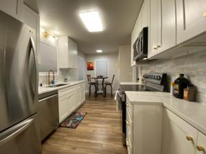 a kitchen with white cabinets and a sink and a refrigerator at Charming Brick Home with bonus space & foosball in Spokane