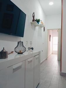 a kitchen with white cabinets and a flat screen tv on the wall at Apartamentos Lax in Almería