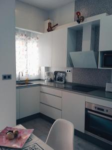 a kitchen with white cabinets and a sink and a chair at Apartamentos Lax in Almería