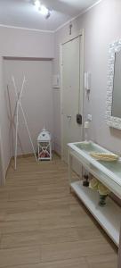 ein weißes Zimmer mit einem Waschbecken und einem Spiegel in der Unterkunft Tindaro Home in Catania