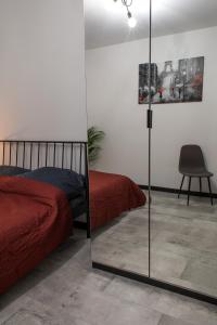 1 dormitorio con espejo, 1 cama y 1 silla en Apartament Black Loft, en Nysa