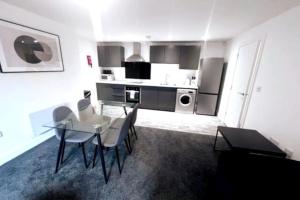 a kitchen with a table and chairs in a room at Lovely 2-BR Flat near Salford Royal in Manchester