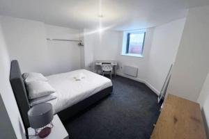 a small room with a bed and a desk at Lovely 2-BR Flat near Salford Royal in Manchester