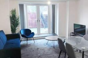 a living room with a blue couch and a table at Lovely 2-BR Flat near Salford Royal in Manchester