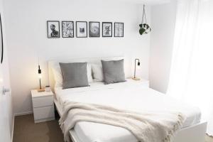 a white bedroom with a large white bed with gray pillows at Beach Side Villa Walk to Shops-Pub-Beach in Byron Bay