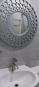 un bagno con specchio sopra un lavandino bianco di Turnbull's Apart Hotel a Consuelo