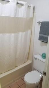 ein Badezimmer mit einem weißen WC und einer Dusche in der Unterkunft OSU 2 Queens Hotel Room 124 Hot Tub Booking in Stillwater