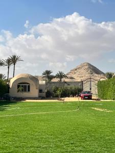una casa in un campo con una montagna sullo sfondo di Sahure Pyramid View lnn a Il Cairo