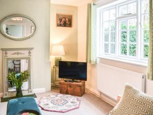 ein Wohnzimmer mit einem TV und einem Fenster in der Unterkunft Coopers Cottage in Louth