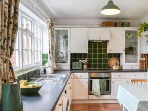 a kitchen with white cabinets and a sink at Coopers Cottage in Louth