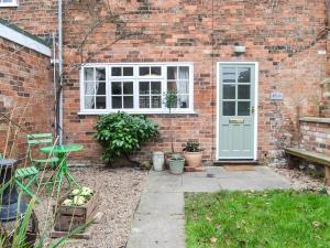 a brick house with a door and a window at Coopers Cottage in Louth