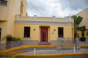 a yellow building with a red door on a street at Hotel Mac Arthur in Tegucigalpa