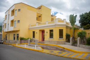 una casa amarilla al lado de una calle en Hotel Mac Arthur, en Tegucigalpa