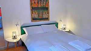 um quarto com uma cama branca e duas mesas em Rooms in Chiassetto em Pisa
