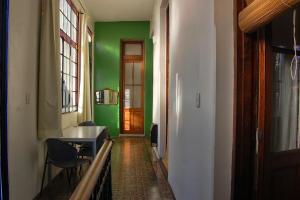 un pasillo con una pared verde, una mesa y sillas en La Boca B&B en Buenos Aires