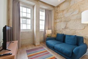 a living room with a blue couch and a tv at RVA - Clerigos Apartments in Porto