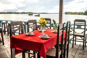 una mesa con un mantel rojo y sillas y vistas al agua en DON DET Souksan Sunset Guesthouse and The Xisland Riverview Studio en Ban Donsôm Tai