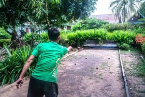 Um homem de camisa verde a atirar um disco voador em DON DET Souksan Sunset Guesthouse and The Xisland Riverview Studio em Ban Donsôm Tai