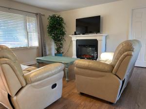 - un salon avec deux chaises, une table et une cheminée dans l'établissement Cozy three bedroom house with fireplace, à Wilmington