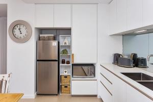 a kitchen with white cabinets and a stainless steel refrigerator at Coastal Souls North Kirra Beach in Gold Coast