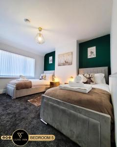twee bedden in een kamer met groene muren bij Large 5 BRH for Contractors,Families and Business free parking in Birmingham