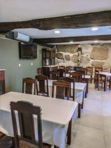 a restaurant with tables and chairs and a stone wall at Costeira Douro in Castelo de Paiva