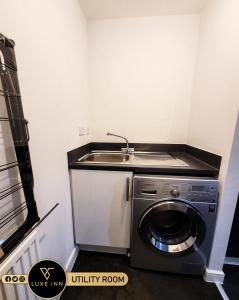 a kitchen with a sink and a washing machine at LUXE INN, Birmingham Airport & NEC, FREE Parking in Marston Green