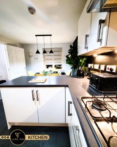 a kitchen with white cabinets and a stove at LUXE INN, Birmingham Airport & NEC, FREE Parking in Marston Green