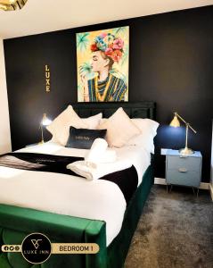 a bedroom with a large bed with a painting on the wall at LUXE INN, Birmingham Airport & NEC, FREE Parking in Marston Green