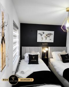 two beds in a room with black and white at LUXE INN, Birmingham Airport & NEC, FREE Parking in Marston Green
