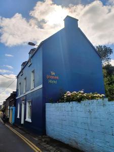 un edificio azul con un cartel en el costado en The Grapevine Hostel en Dingle