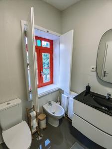 La salle de bains est pourvue de toilettes blanches, d'un lavabo et d'une fenêtre. dans l'établissement Costeira Douro, à Castelo de Paiva