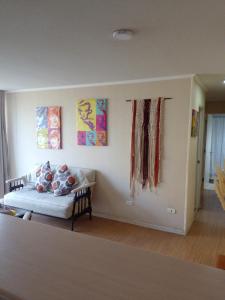 sala de estar con sofá y pinturas en la pared en Departamento Full Equipado y Central, en Talca