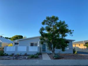 a white house with a tree in front of it at Serenity by the Sea in Busselton