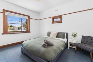 1 dormitorio con cama, ventana y silla en Charming Cottage Escape - Pet friendly!, en Geelong West