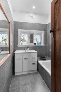 y baño con bañera, lavabo y bañera tubermottermott. en Charming Cottage Escape - Pet friendly!, en Geelong West