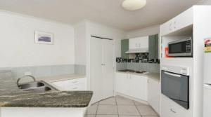 a white kitchen with a sink and a microwave at Grande Florida - Hosted by Burleigh Letting in Gold Coast