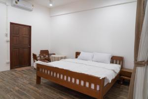 een slaapkamer met een bed en een houten vloer bij Sakk - Lanna Heritage Stay in Ban Mae Hom