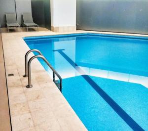 a large blue swimming pool in a building at Beautiful Hi-rise, King size, HS Wi-Fi, pool, gym in Mexico City