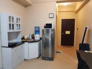 a kitchen with a refrigerator with a microwave on top of it at Keys N Places @ Avida Aspira in Cagayan de Oro