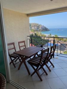 un tavolo in legno con sedie e un balcone con vista sull'oceano. di Bay View Grand Residencial 602 Sur a Ixtapa