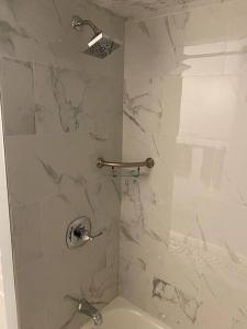 La salle de bains est pourvue d'une douche et de murs en marbre blanc. dans l'établissement Rockaway 3 bedroom suite by the Sea., à Wave Crest