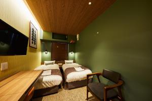 two beds in a room with green walls at Hotel TORACO konohana in Osaka