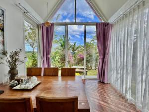 a dining room with a table and a large window at MeGarden Daknong in Gia Nghĩa