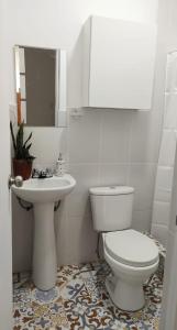 a white bathroom with a toilet and a sink at Edificio Sánchez Cerro in Piura