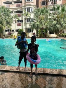 two children standing in the water at a swimming pool at D Nish Homestay in Tawau